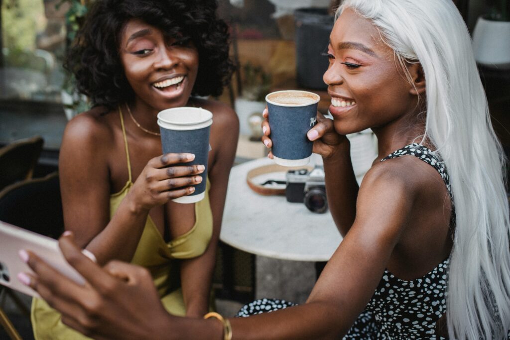 Two happy female friends having a coffee and taking a selfie