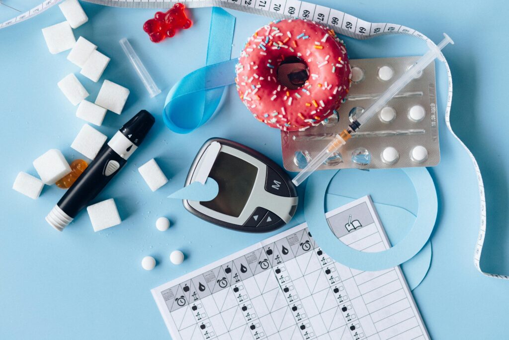 An image depicting diabetes by showing a doughnut, sugar cubes and a blood sugar level checker