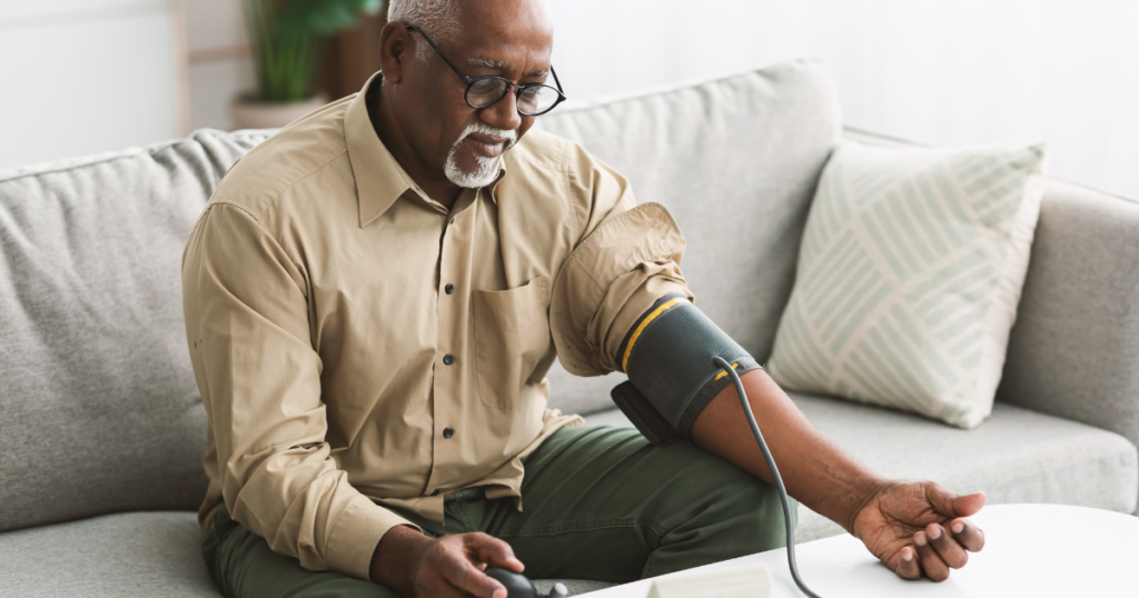 An older black gentleman checking his blood pressure by himself