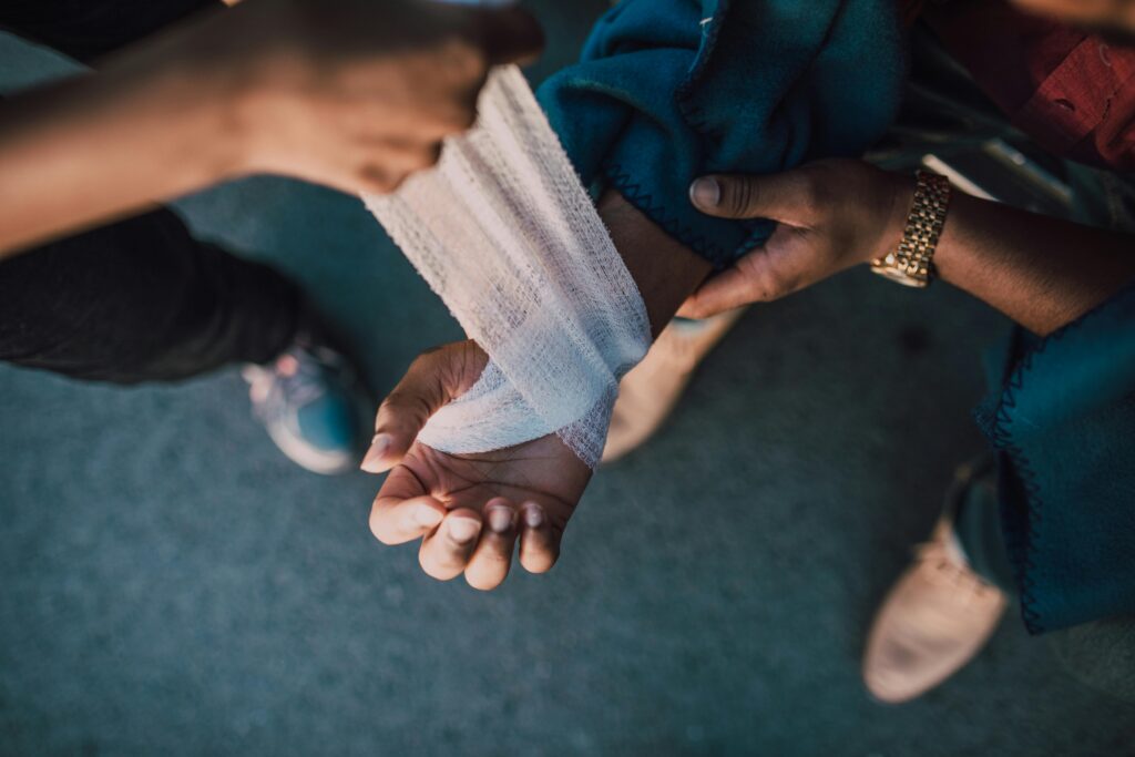 A person's arm bandaging another person's hand